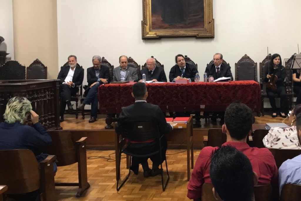 O mestrando é submetido à avaliação da banca examinadora, na Faculdade de Direito da UFMG (Foto: Divulgação)