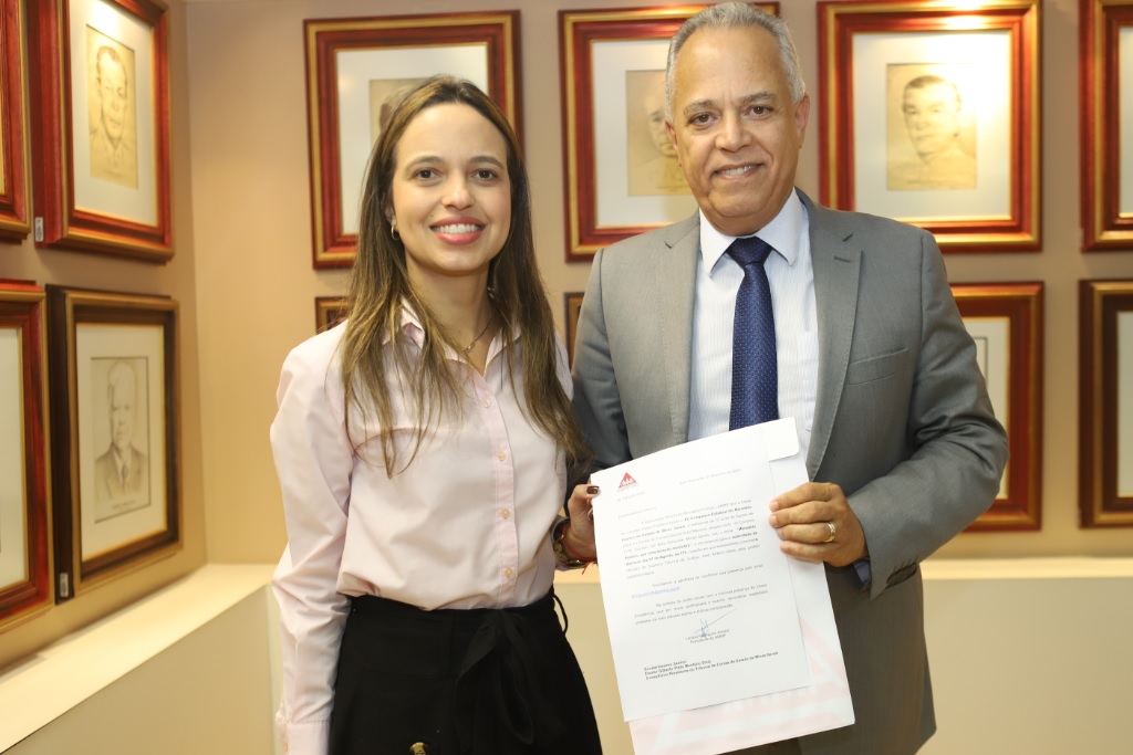 Presidente Gilberto Diniz recebe convite das mãos da  promotora de Justiça Larissa Amaral (Foto: Vinícius Dias)