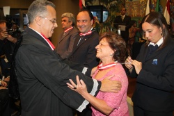 Conselheiro em exercício Gilberto Diniz entrega a medalha à artista plástica Yara Tupinambá